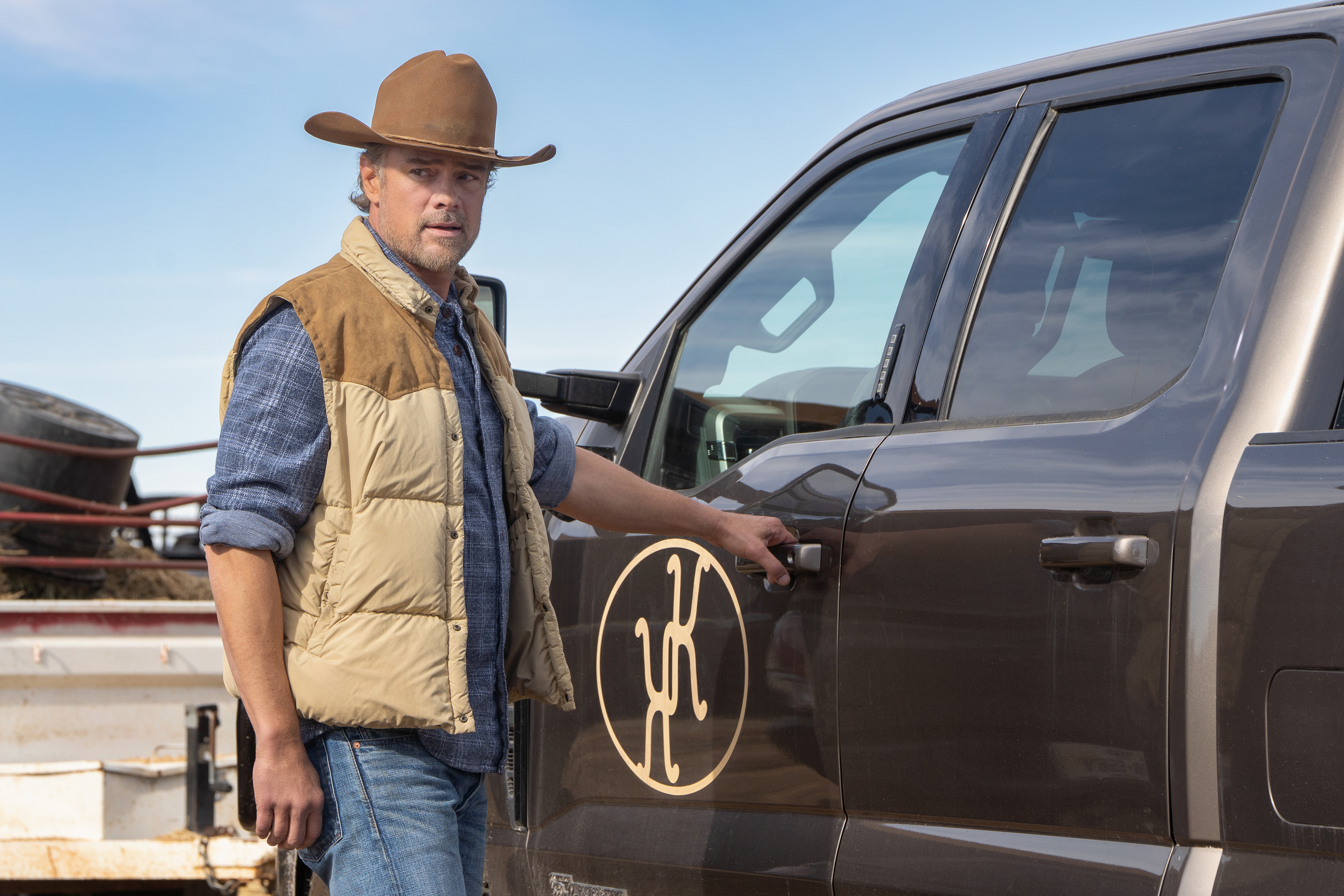 Josh Duhamel as Staten, grabbing the door handle of a pickup truck with a symbol of interlocking K's, in Episode 207 of Netflix's 'Ransom Canyon' season 2.
