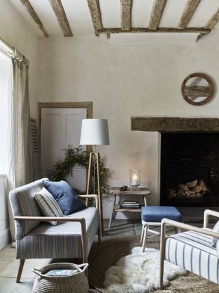 farmhouse living room with beams and fireplace, sofa, armchair and rug
