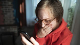 A woman looking at her phone with a shocked and scared expression