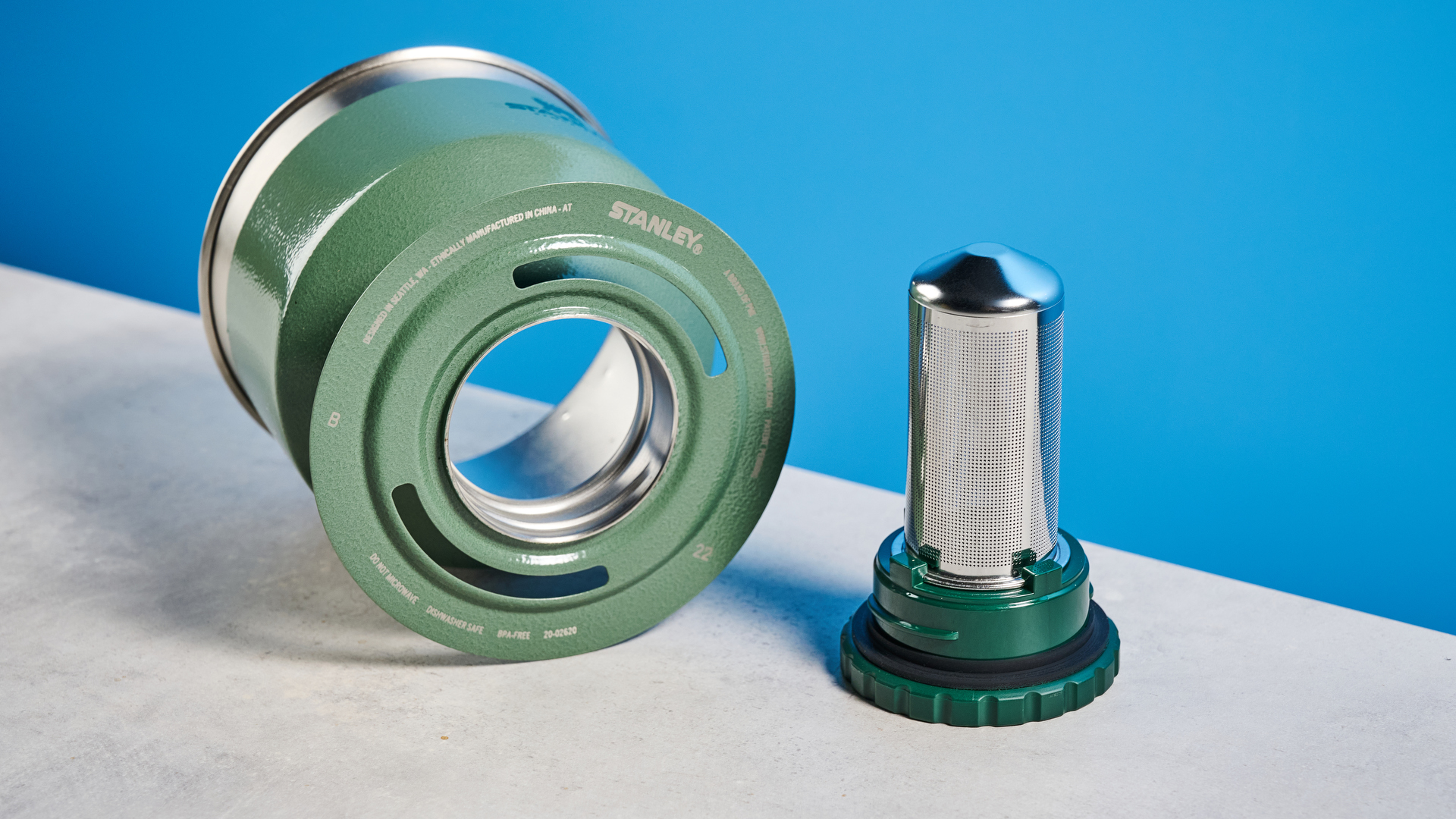 the stanley perfect brew pour over coffee maker in green, photographed with its companion travel mug and with the metal built in filter