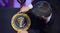 An aide places the presidential seal on Joe Biden's lectern