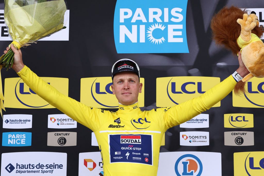 Soudal Quick-Step's Belgian rider Tim Merlier celebrates on the podium wearing the overall leader's yellow jersey after winning the 1st stage of the Paris-Nice cycling race, 156,1 km between Le Perray-en-Yvelines and Le Perray-en-Yvelines, on March 9, 2025. (Photo by Anne-Christine POUJOULAT / AFP)