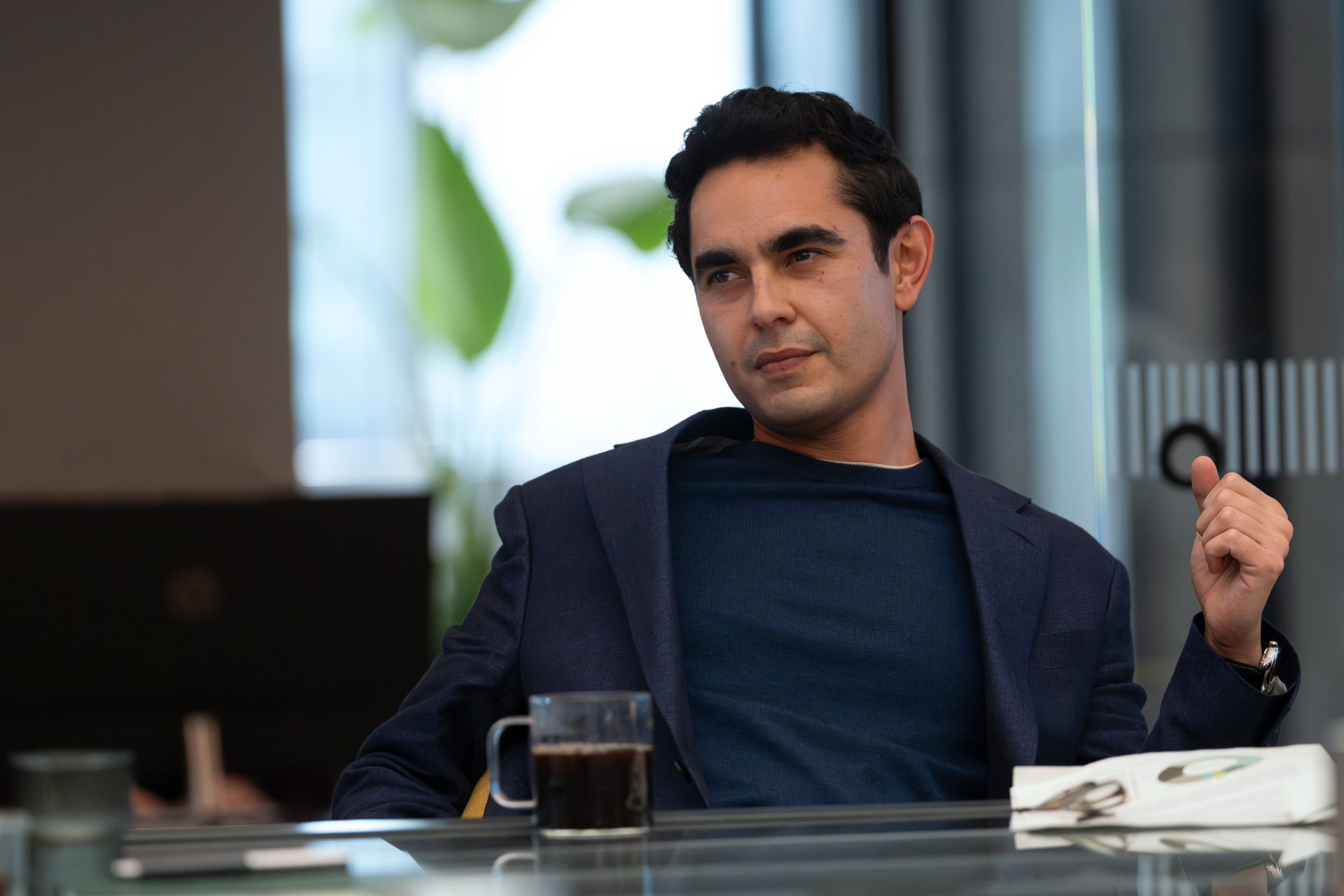 max minghella in a blazer drinking cofee at an office desk in industry season 4