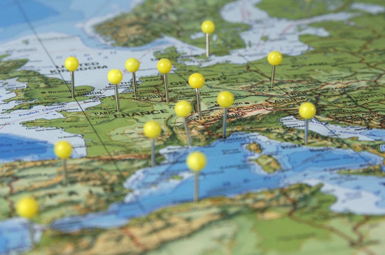 Paper map showing different countries in Europe including France and Germany with yellow push pins