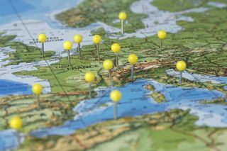 Paper map showing different countries in Europe including France and Germany with yellow push pins