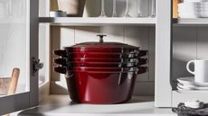 Staub Stackable Cast Iron Set in grenadine red in a kitchen cabinet