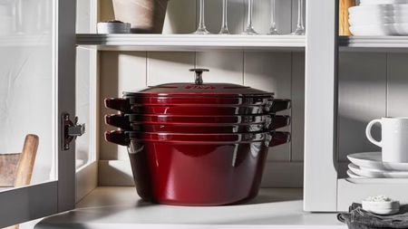 Staub Stackable Cast Iron Set in grenadine red in a kitchen cabinet