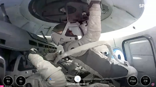 Hatch and tether are checked prior to historic spacewalk