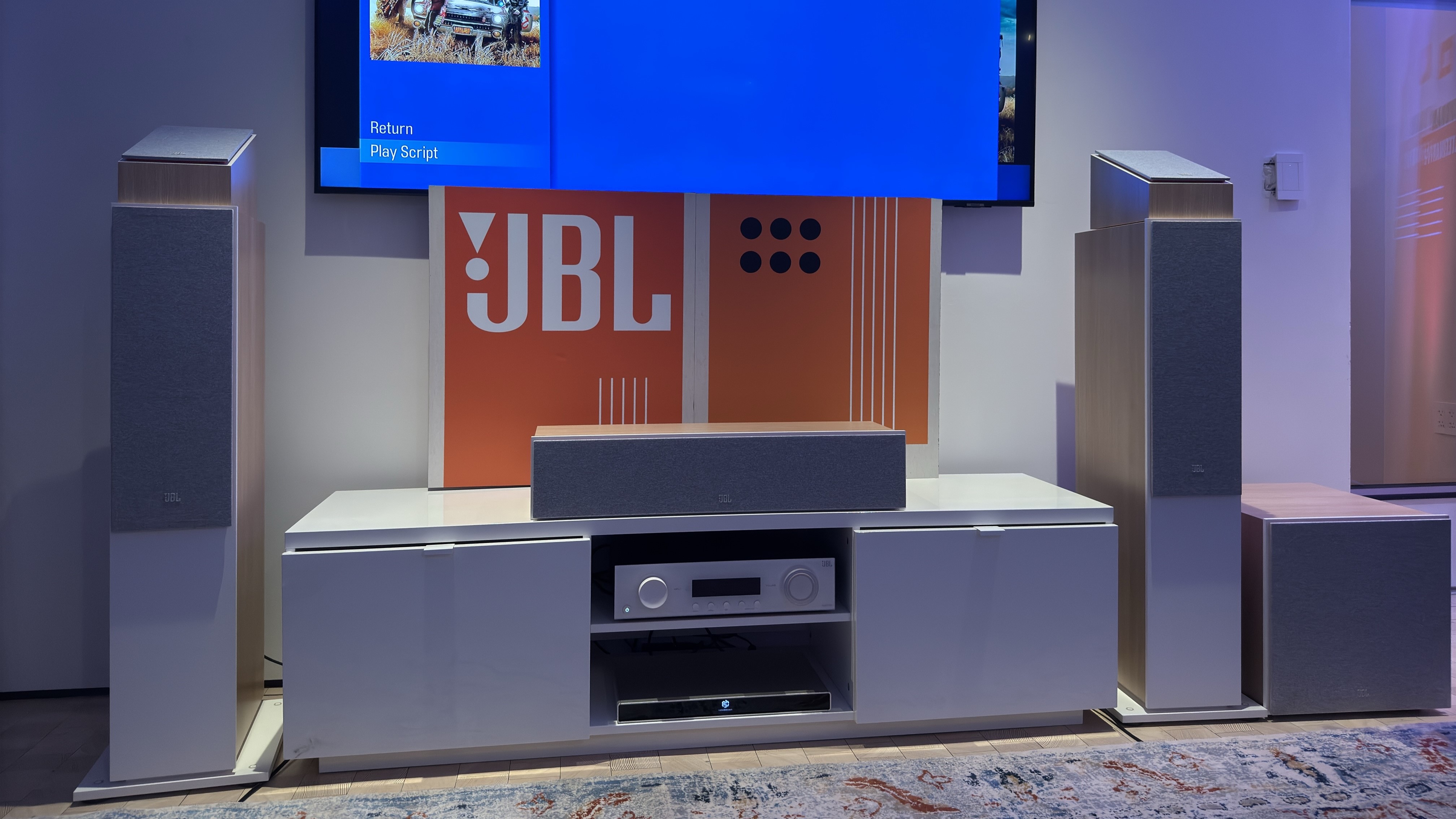 Un moderno receptor JBL AV y altavoces Stage 2 están configurados con el televisor