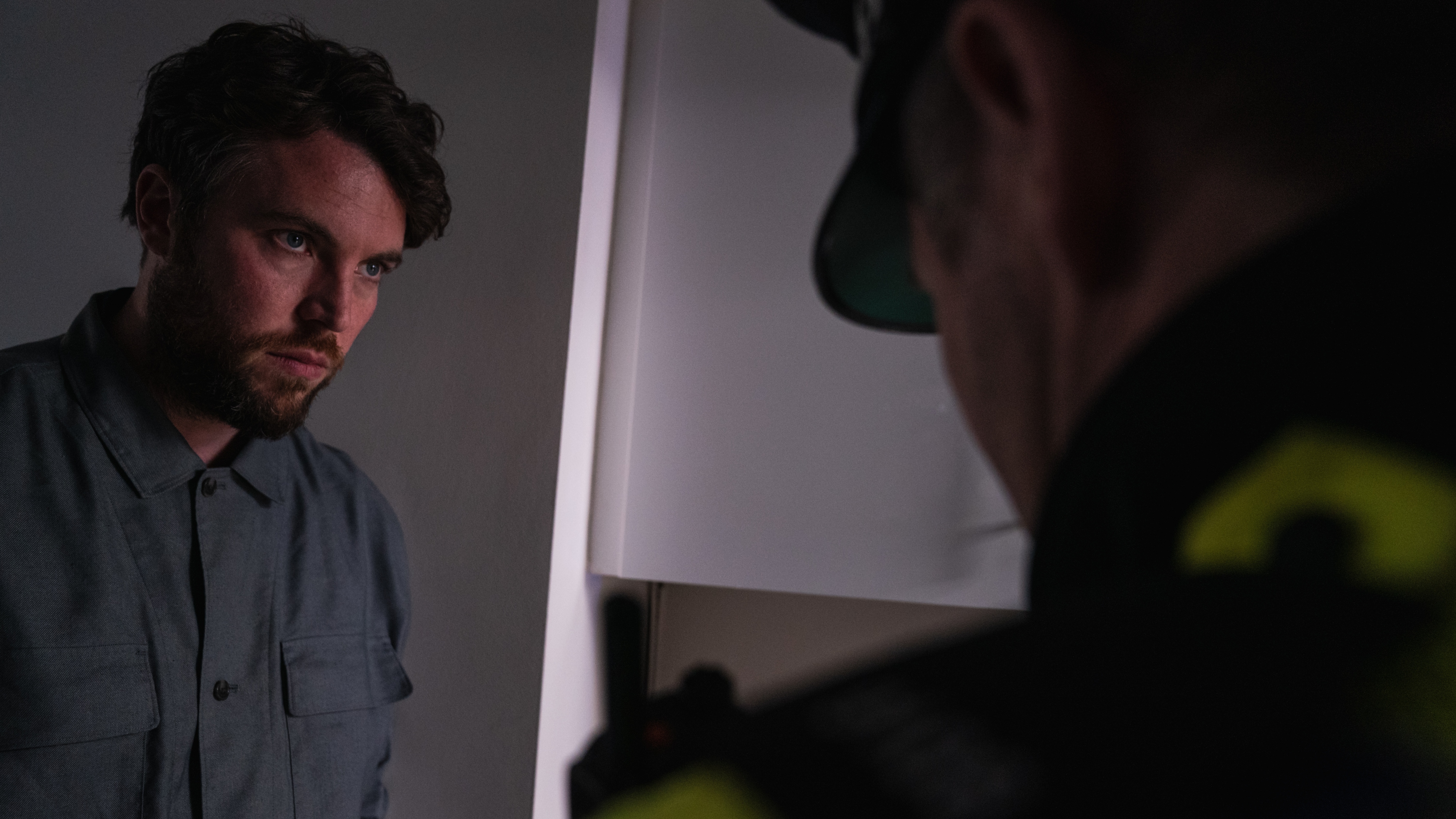 James looking upset as he is questioned by a police officer in Maria's kitchen