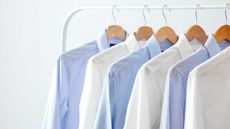Blue and white dress shirts hanging on clothes rack
