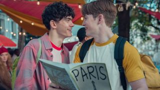 Nick and Charlie holding a Paris map and smiling at each other. 