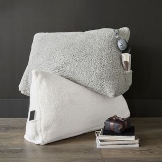 Cozy Wedge Pillow against a black wall.