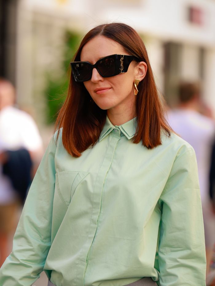 A woman at London Fashion Week wearing a green shirt and YSL sunglasses with copper hair