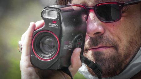 Man with sunglasses using Yashica Samurai x3.0 half-frame film camera outdoors