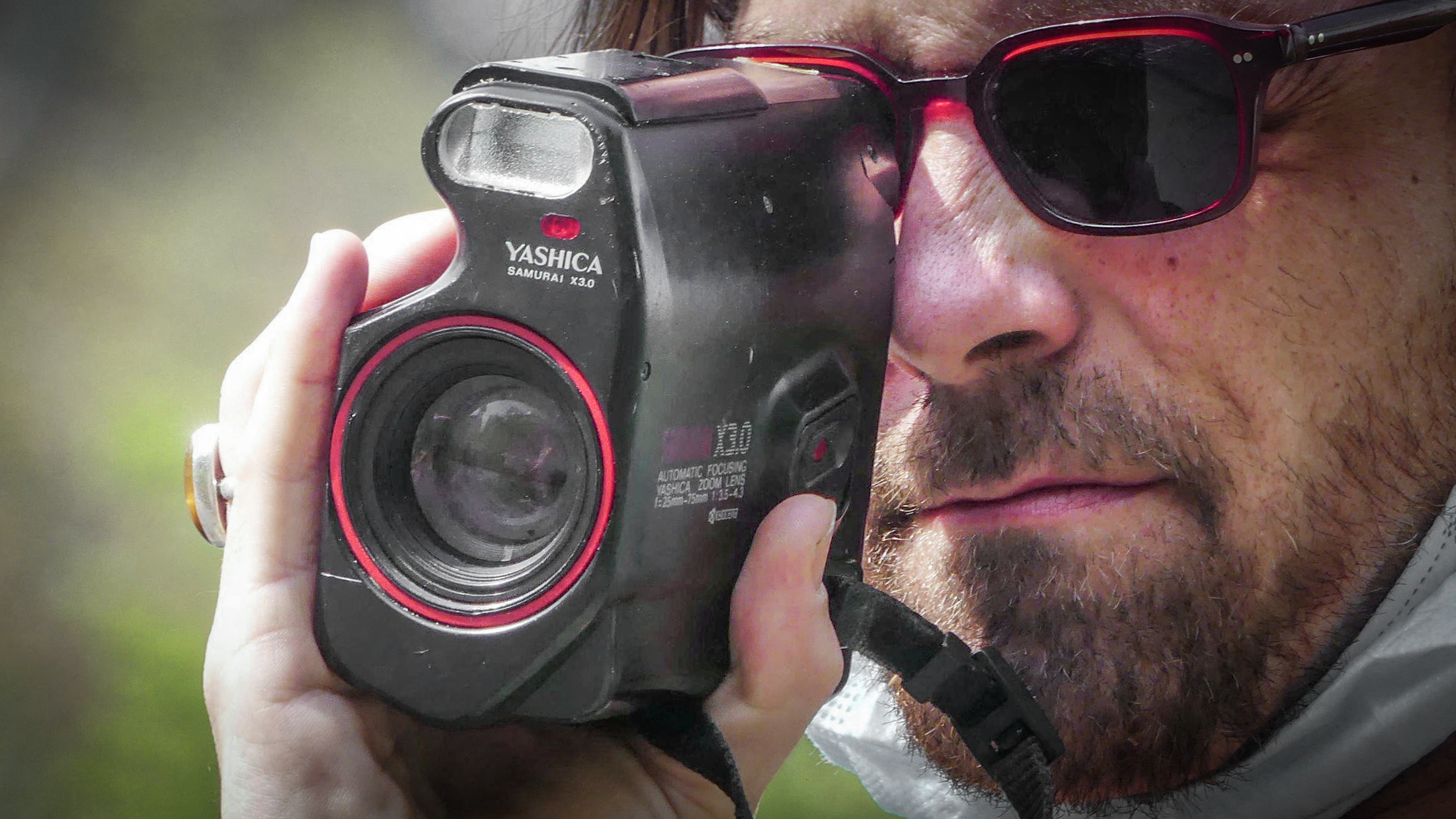 Man with sunglasses using Yashica Samurai x3.0 half-frame film camera outdoors