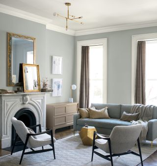 An eggshell grey living room with pale blue sofa and gold accessories