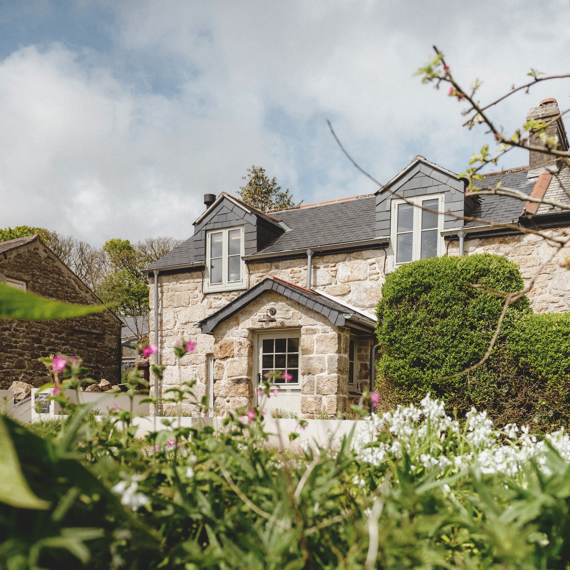 exterior of Cornish stone cottage with stone porch and dormer windows in roof