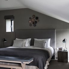Grey bedroom with decorative plates above bed
