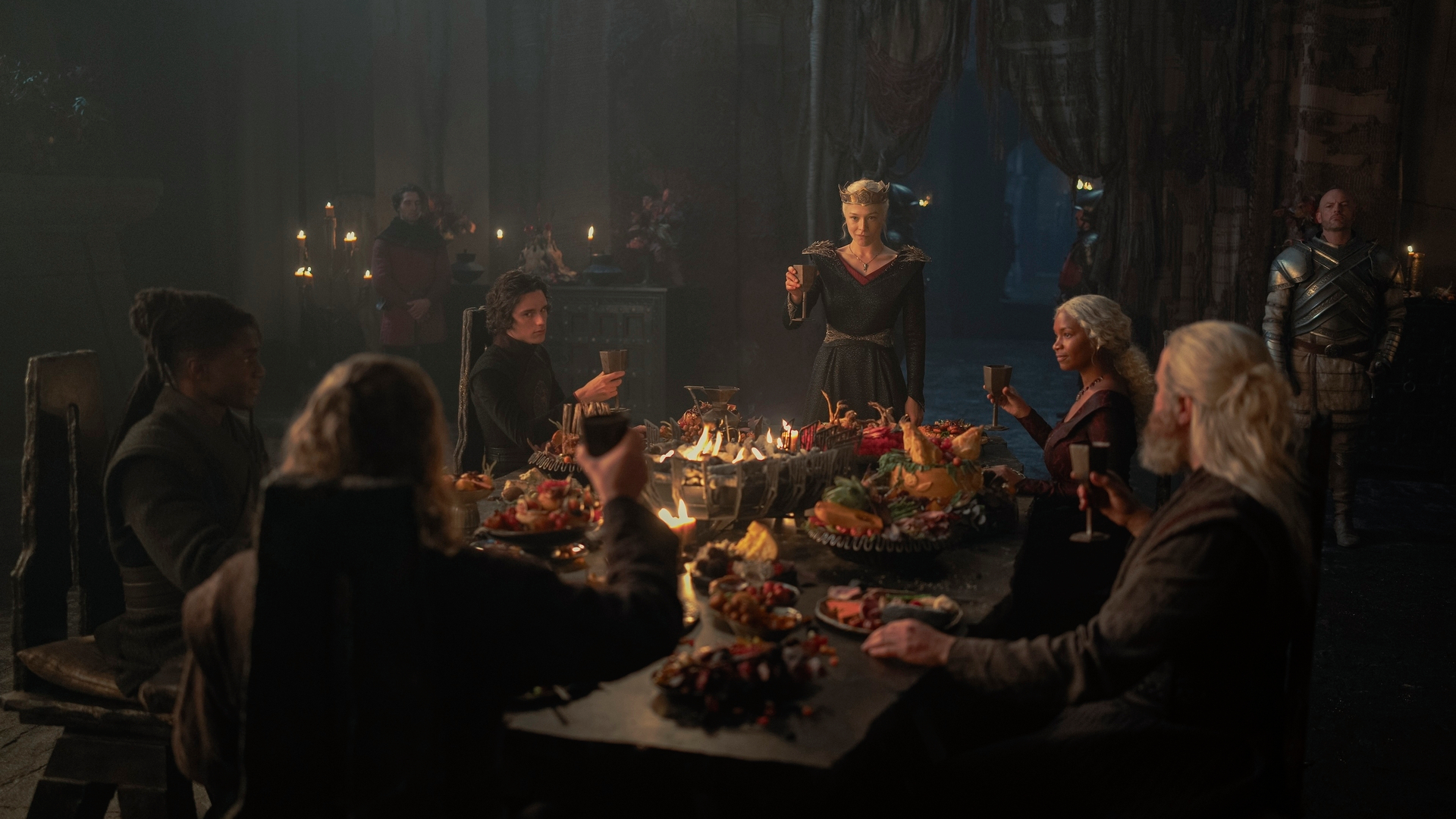 Addam de Hull (Clinton Liberty), Jacaerys (Harry Collett) Rhaenyra (Emma D'Arcy), Baela (Bethany Antonia), Ulf (Tom Bennett) et Hugh Hammer (Kieran Bew) assis autour de la table à manger dans le 