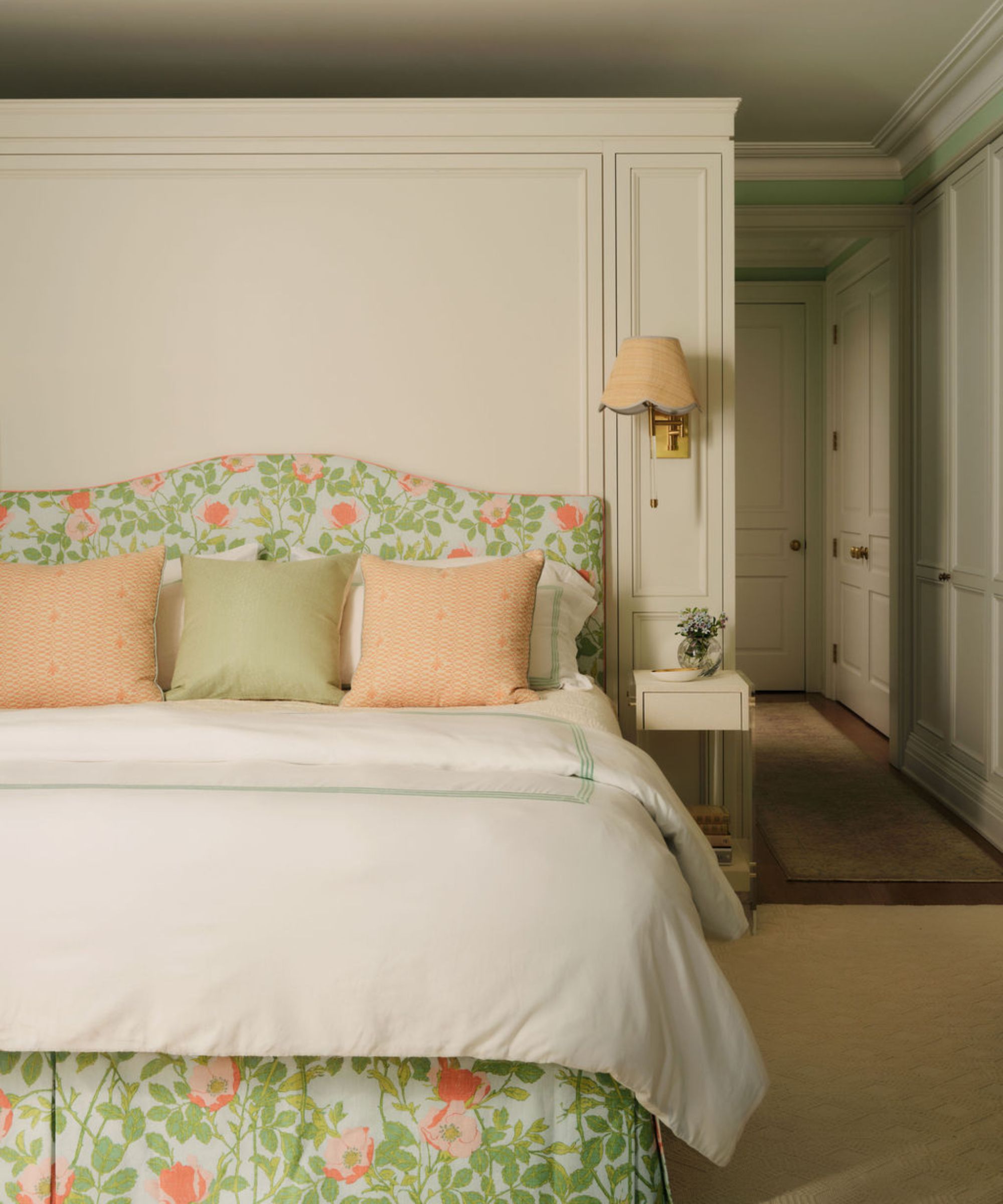 a neutral, soft green and pink bedroom with a floral upholstered bed