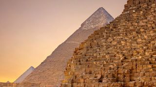 A side view of the Pyramids of Giza, Egypt at sunset.