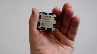 A masculine hand holding an AMD Ryzen 9 9950X3D processor