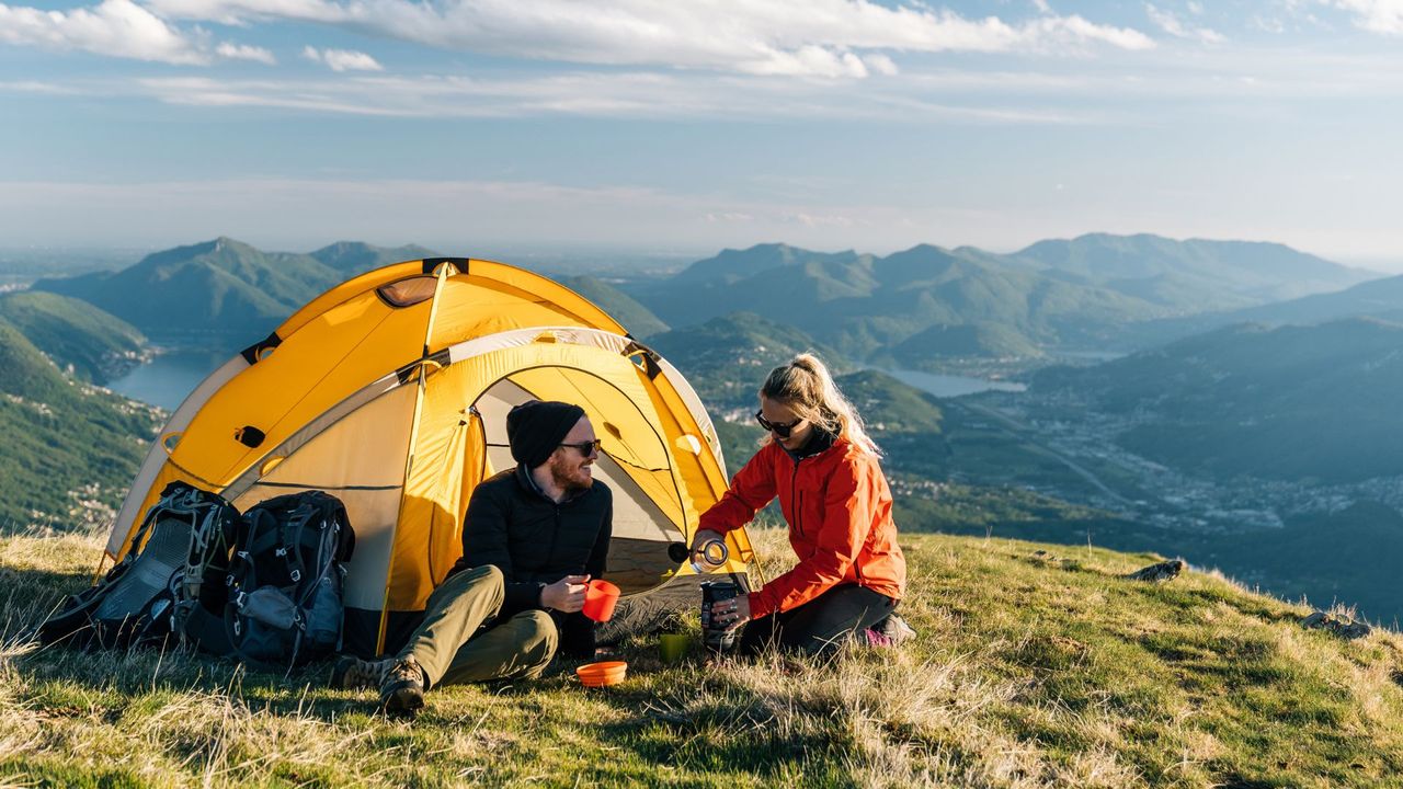 Man and woman sitting outside their tent outside in the sun