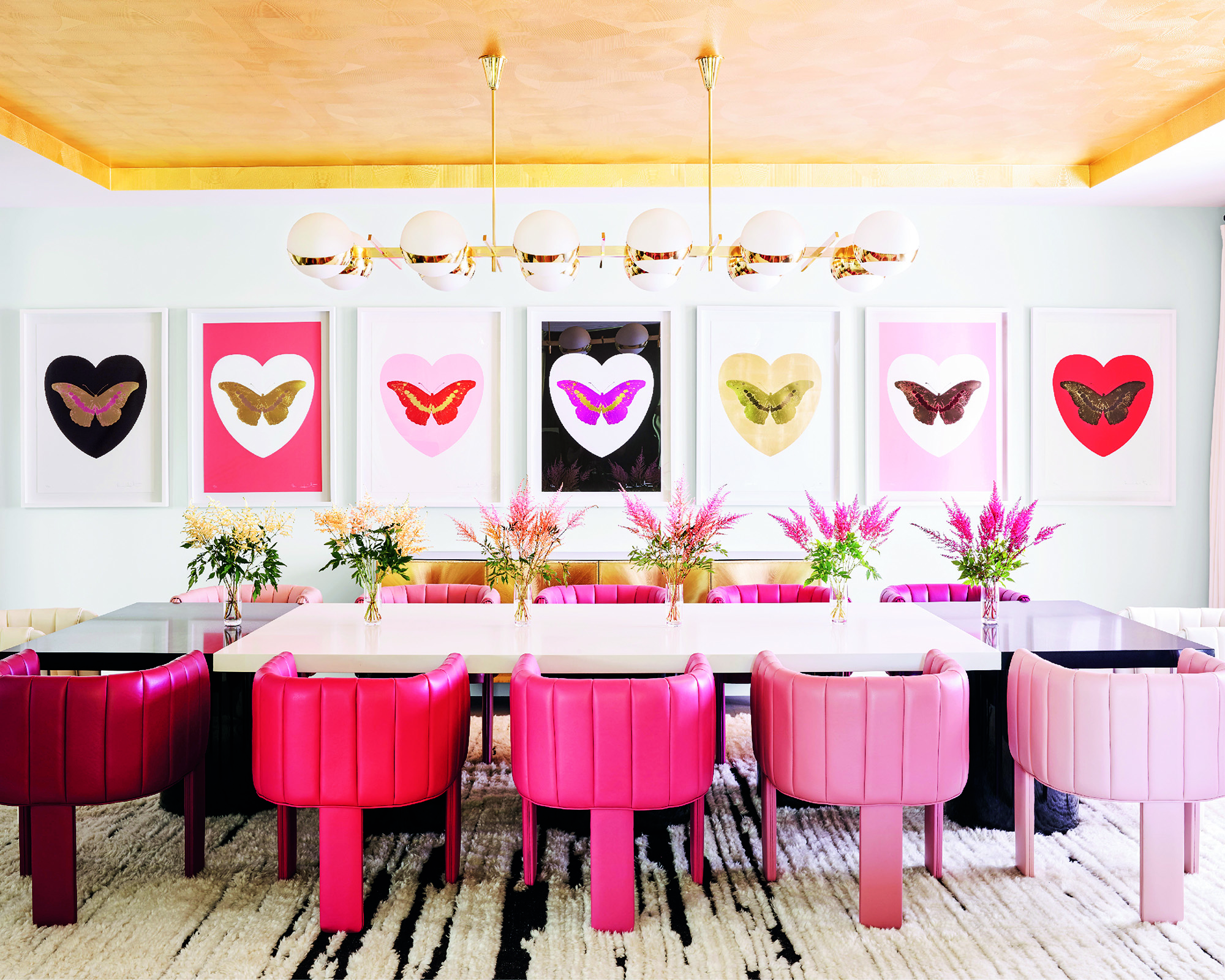 kylie jenner's large dining room with pink dining chairs and white table with pink art on the walls