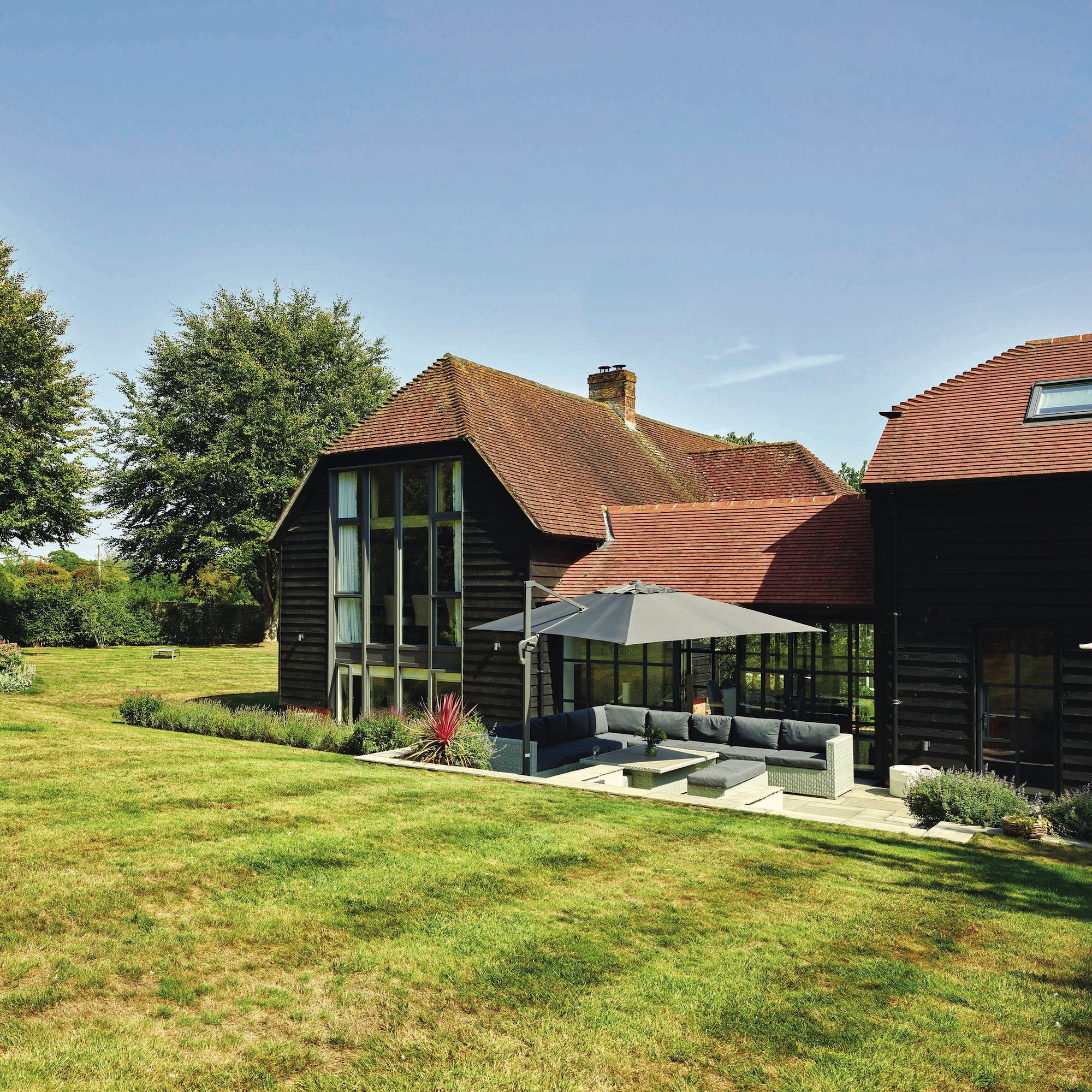 exterior of converted barn showing large windows and garden setting