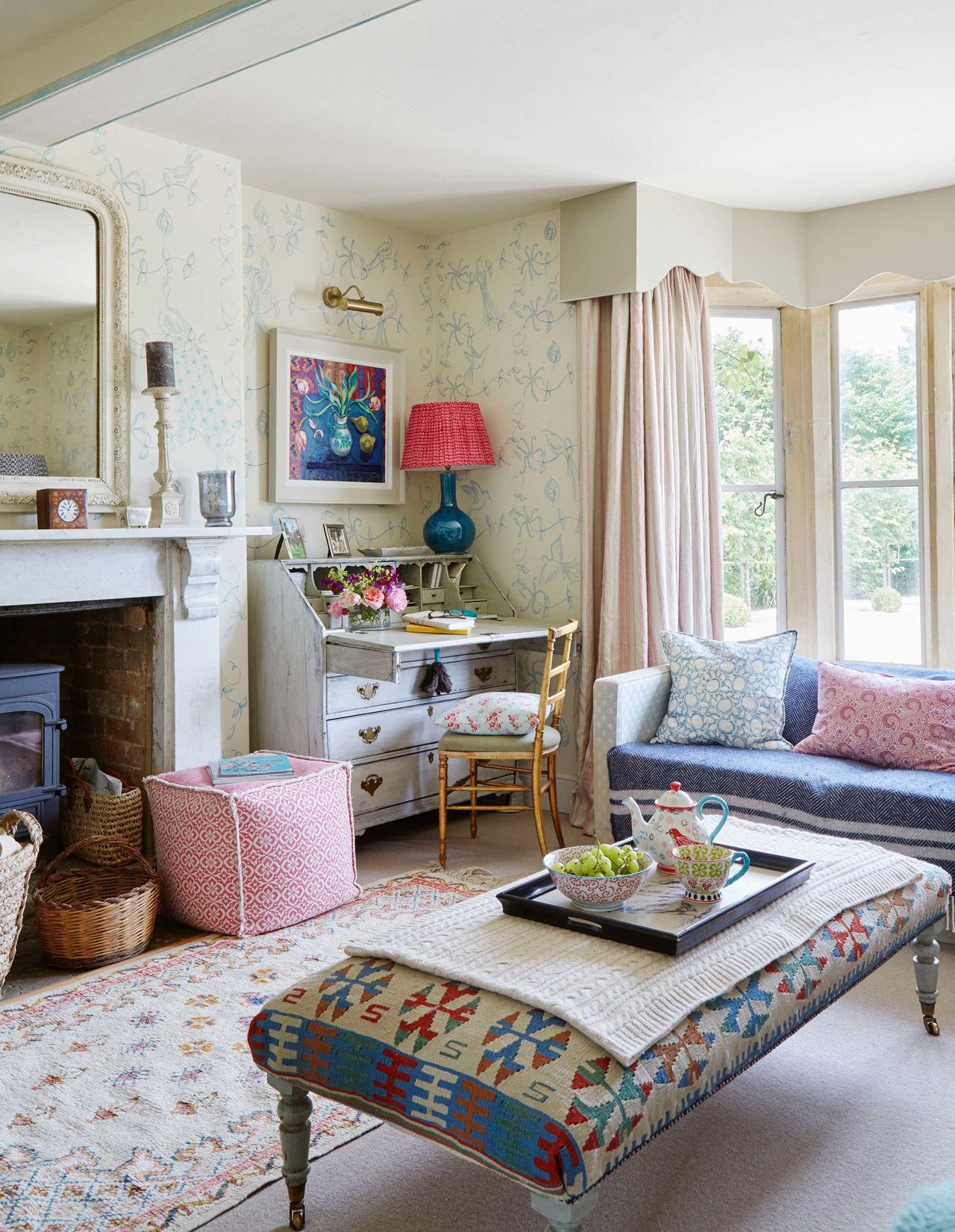 A cozy farmhouse style living room with fireplace, sofa, footstool and home office desk area