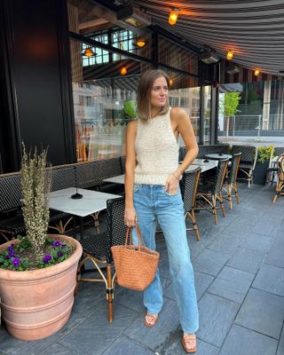 Bethany Holmes trug hell gewaschene Jeans, braune Sandalen, eine braune Strohtasche und ein gestricktes Tanktop.