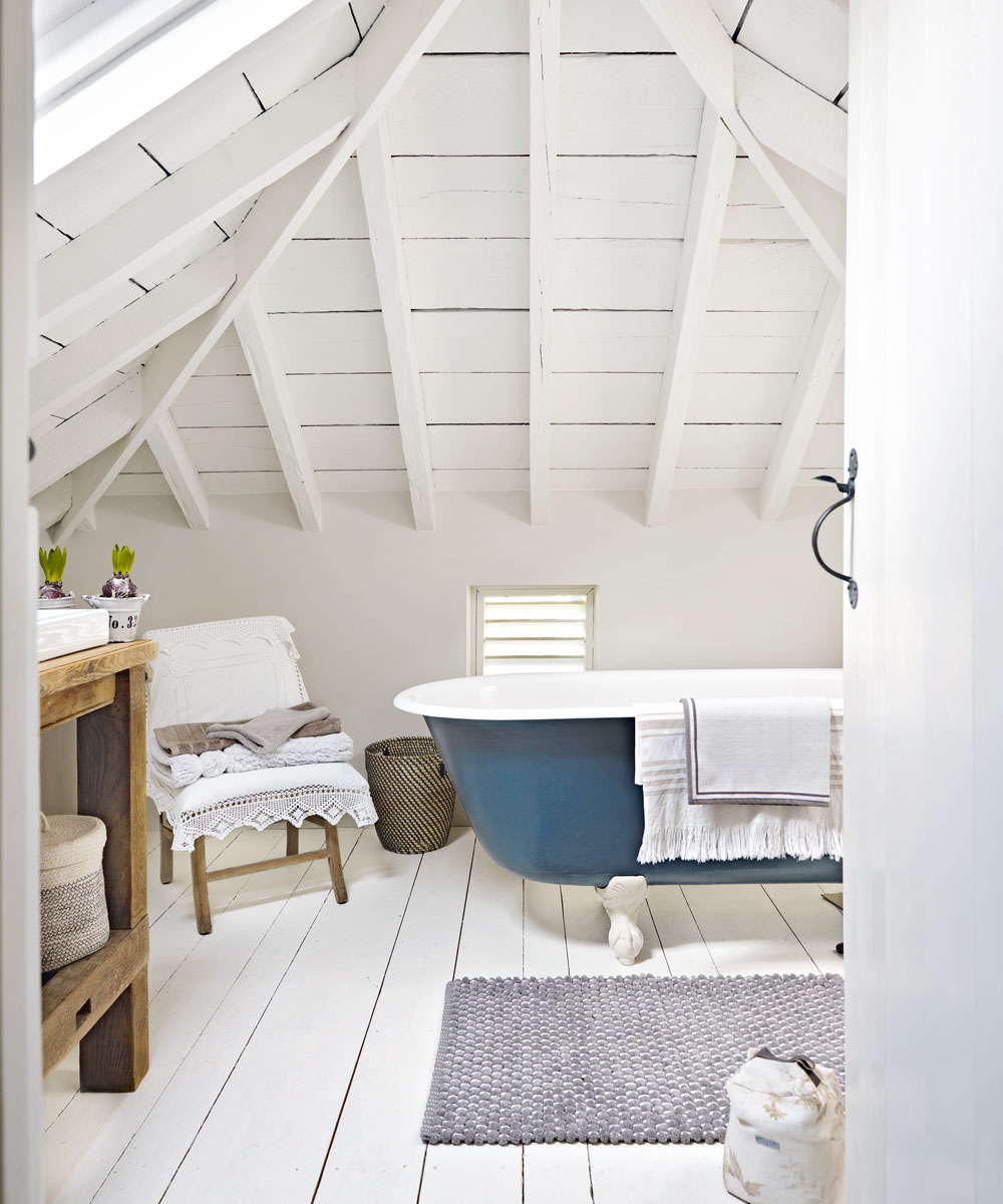 attic bathroom with wooden flooring and blue bathtub