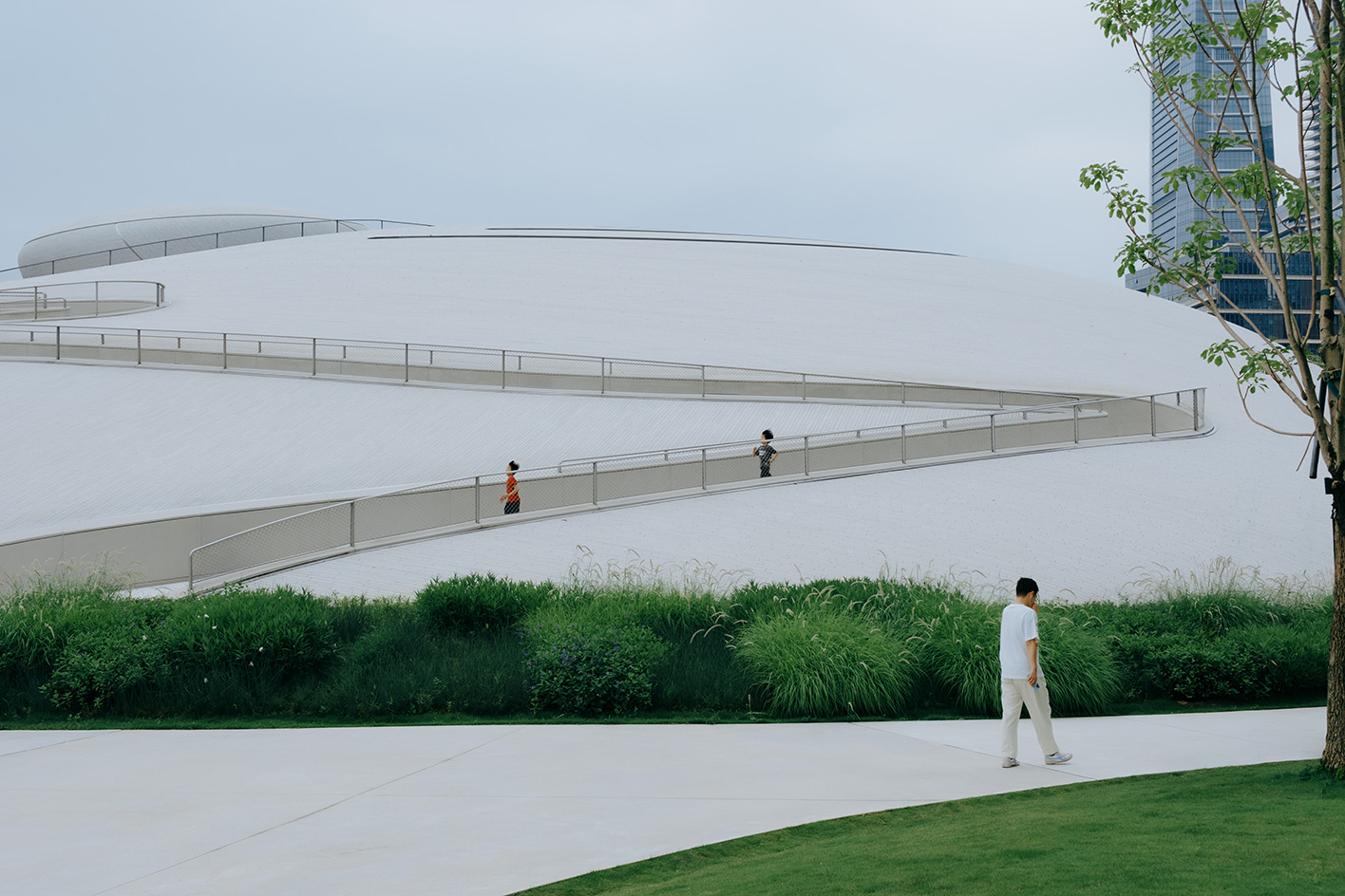 view of MAD Shenzhen Bay Culture Square, all white volumes and curves in a green park