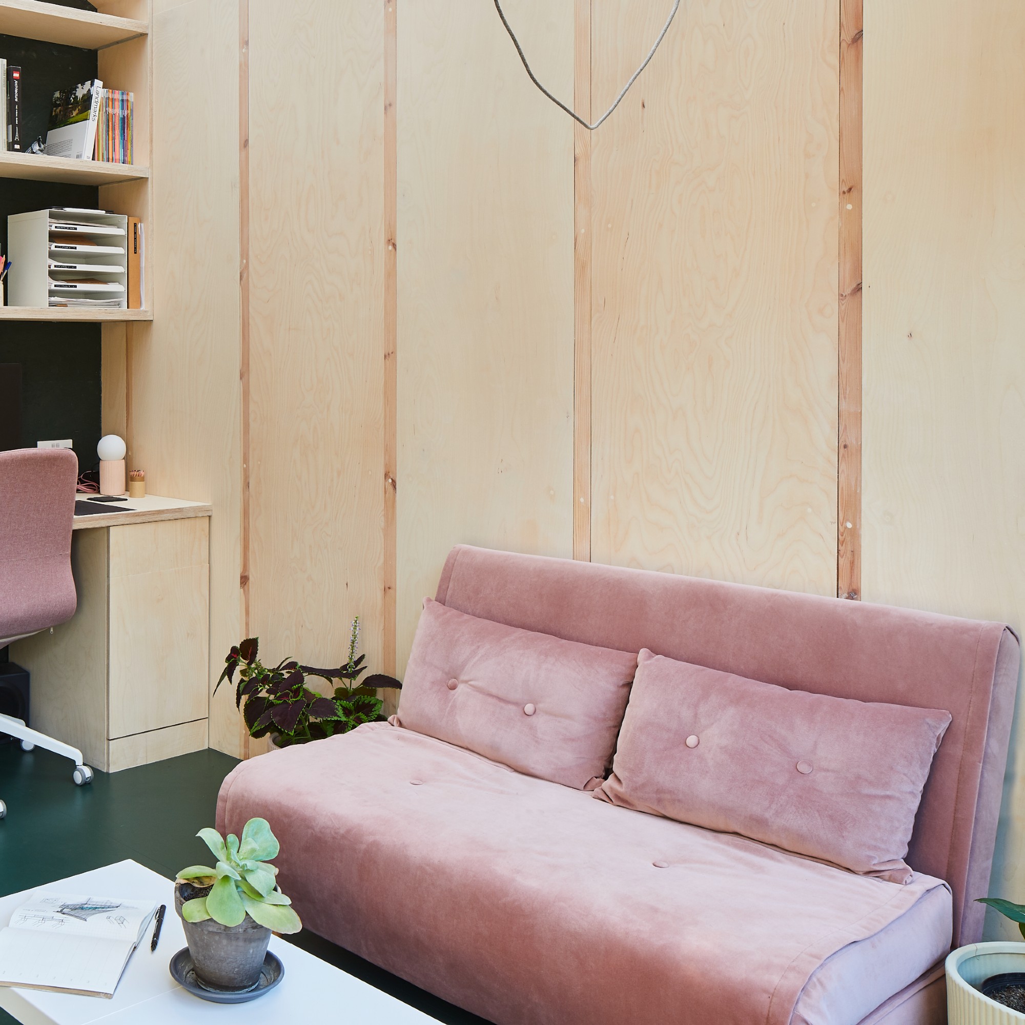 A pink velvet sofa bed in a home office with wall panelling