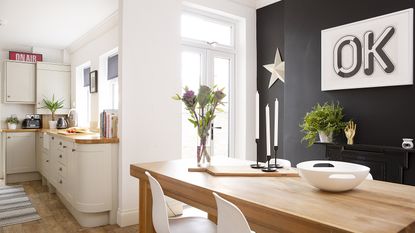 dining area with black feature wall and a shaker style kitchen
