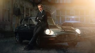 Bertie Carvel in a dark suit leans against a green car as DCI Adam Dalgliesh in Dalgliesh season 2