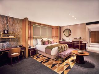 Platform bed on a geometrically designed carpet with a marble wall and wooden wall behind it