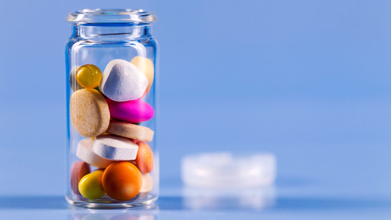 Glass jar filled with immunity supplements on a blue background