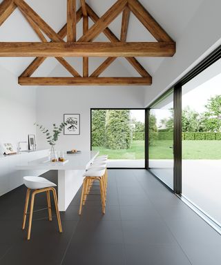 large format matte tiles in a white kitchen with island wood beams and large bifold windows