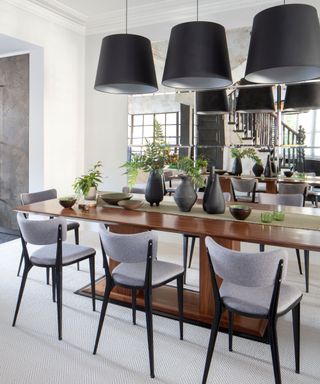 Modern dining room with dark wooden dining table, black and gray dining chairs, black pendant lighting, gray carpet