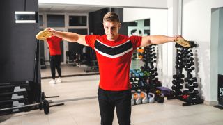 Man performs lateral raise using small and light weight plates in gym