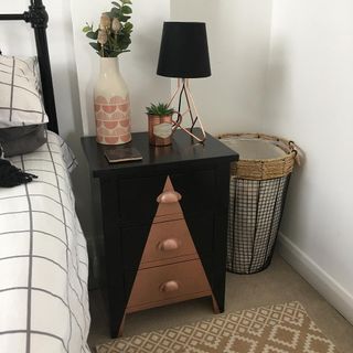 bedrom with black wooden bedside table and flower in vase