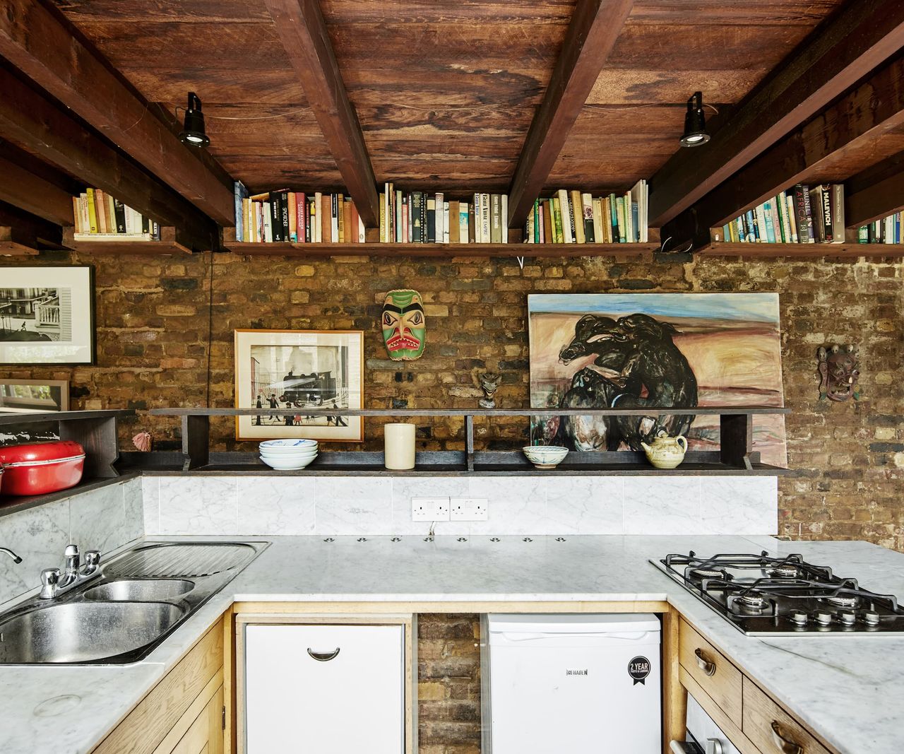 A kitchen island with white marble top and appliances underneath