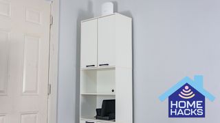 A modified kitchen pantry cabinet filled with networking gear and a mini PC with a Home Hacks badge