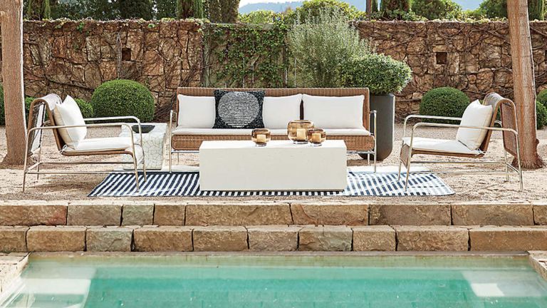 一条黑色和白色条纹的户外地毯，现代藤条休息室坐落在游泳池的一侧