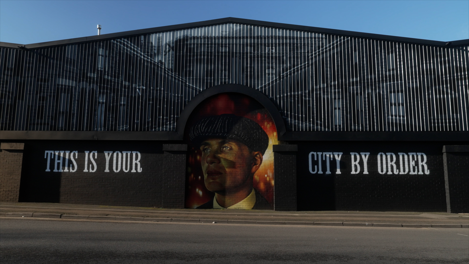 A picture of Tommy Shelby from Peaky Blinders painted on the side of a building