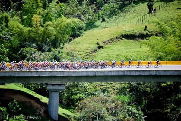 The peloton crosses a bridge in the Colombian countryside