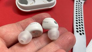 Sony WF-C700N wireless earbuds in the hand over a red table