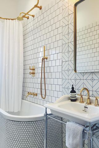 Small bathroom tile ideas A white bathroom featuring white tiles all over and brass hardware